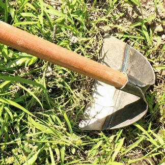 Gardener using a garden hoe to remove weeds from soil in a vegetable garden