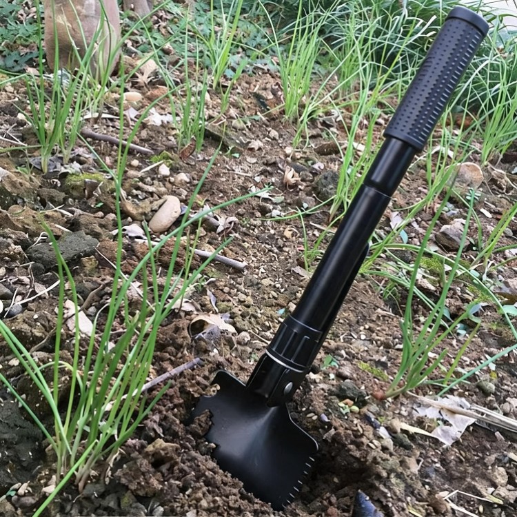 Black folding shovel being used for gardening and digging soil