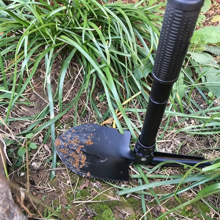 Green folding shovel in use for planting and digging in garden